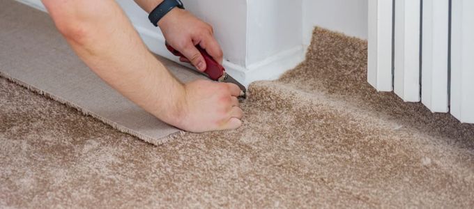 professional flooring services - man cutting carpet around corner